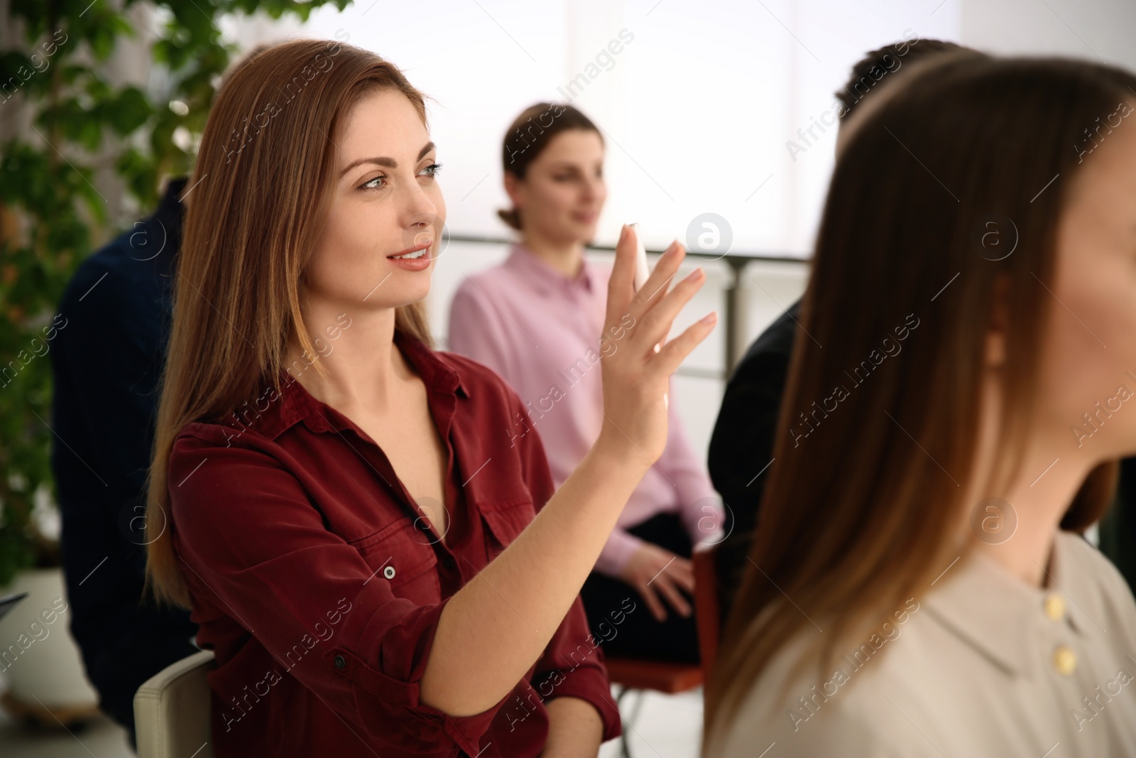 Photo of Woman raising hand to ask question at business training indoors