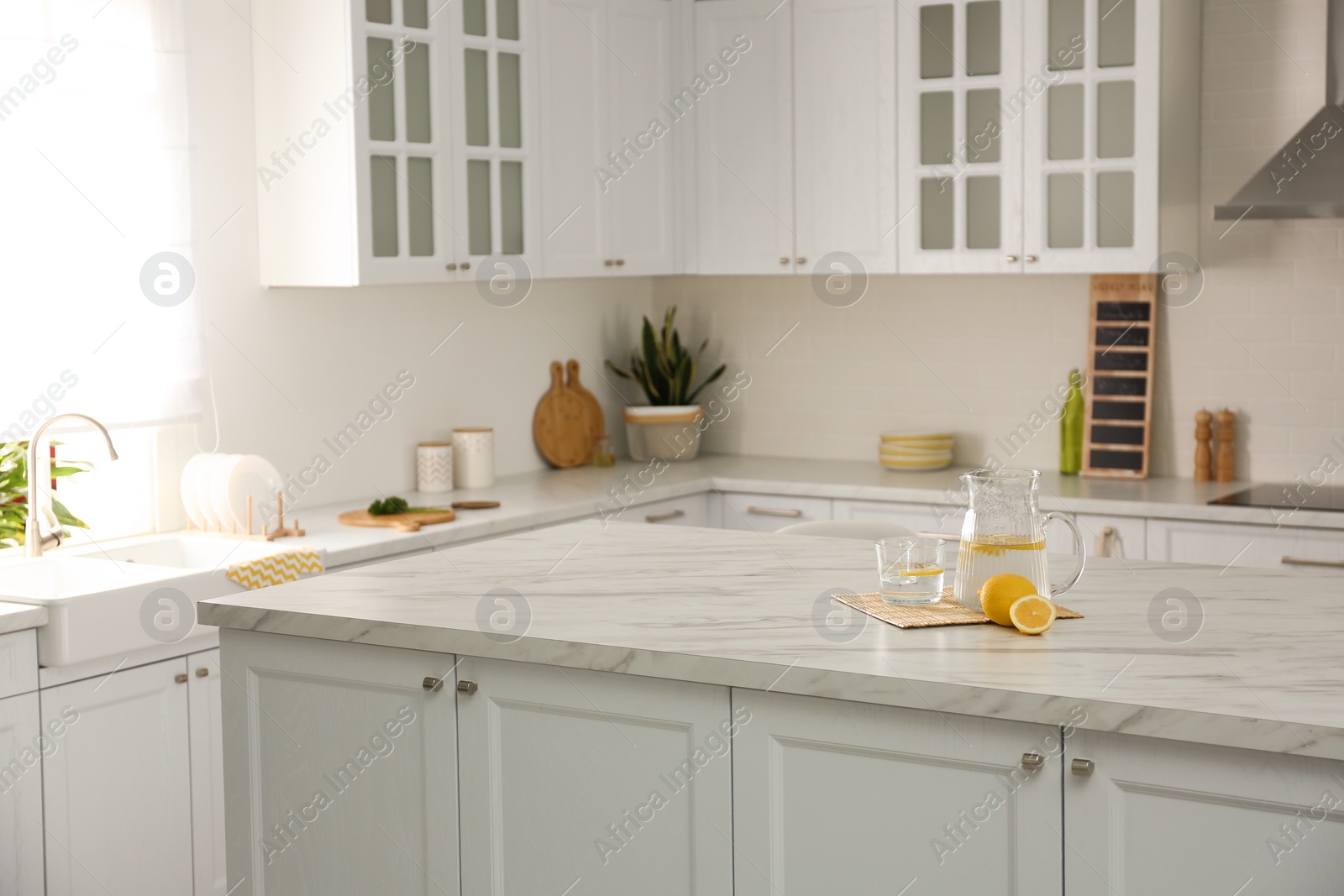 Fresh lemonade on white marble table in kitchen. Stylish interior design Photo of Fresh lemonade on white marble table in kitchen. Stylish interior design