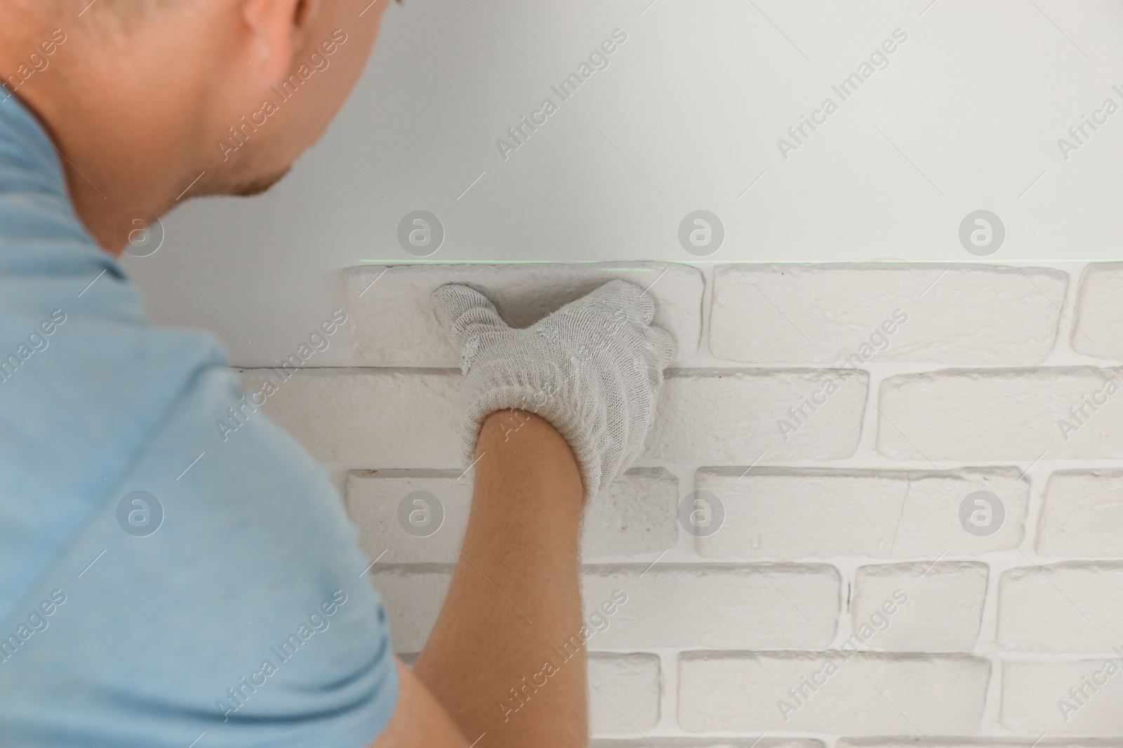 Photo of Worker installing decorative wall tiles in room, closeup