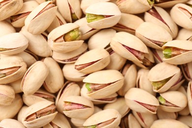 Photo of Tasty unpeeled pistachios as background, top view