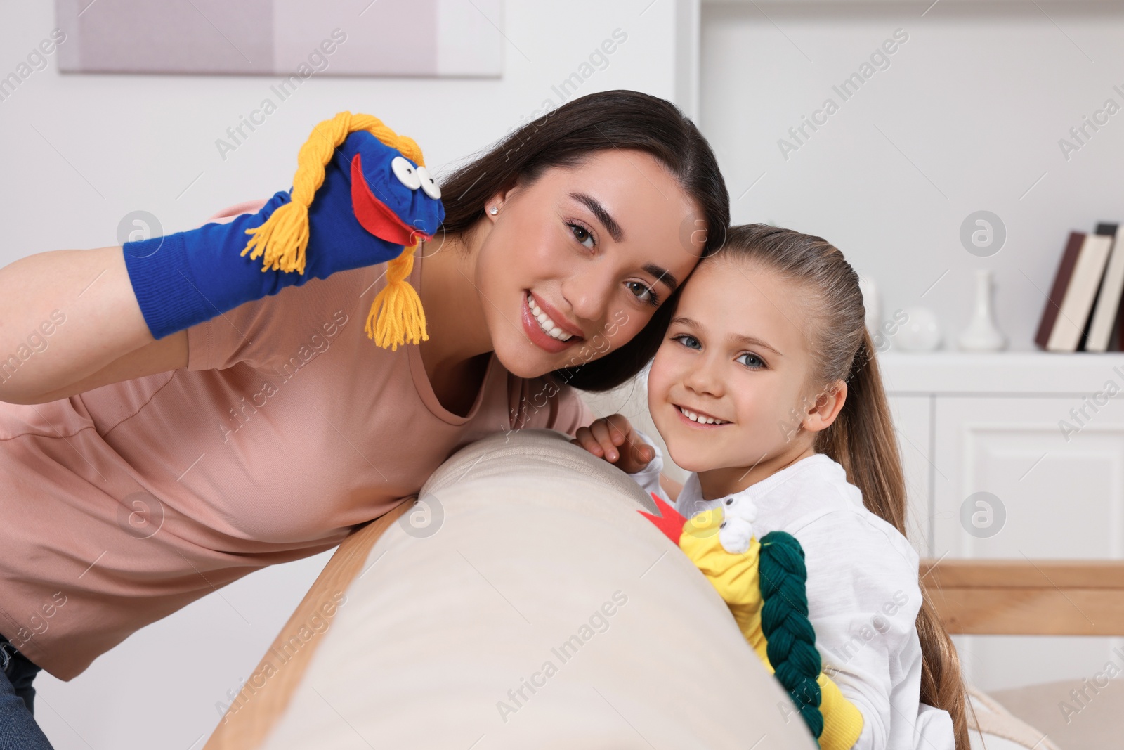 Photo of Happy mother and daughter playing with funny sock puppets together at home