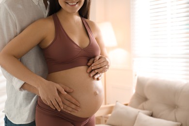 Photo of Man touching his pregnant wife's belly at home, closeup. space for text