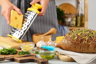 Tasty homemade garlic bread with cheese and blurred woman on background