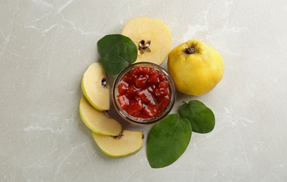 Delicious quince jam and fruits on light grey marble table, flat lay