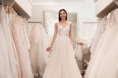 Photo of Woman trying on beautiful wedding dress in boutique