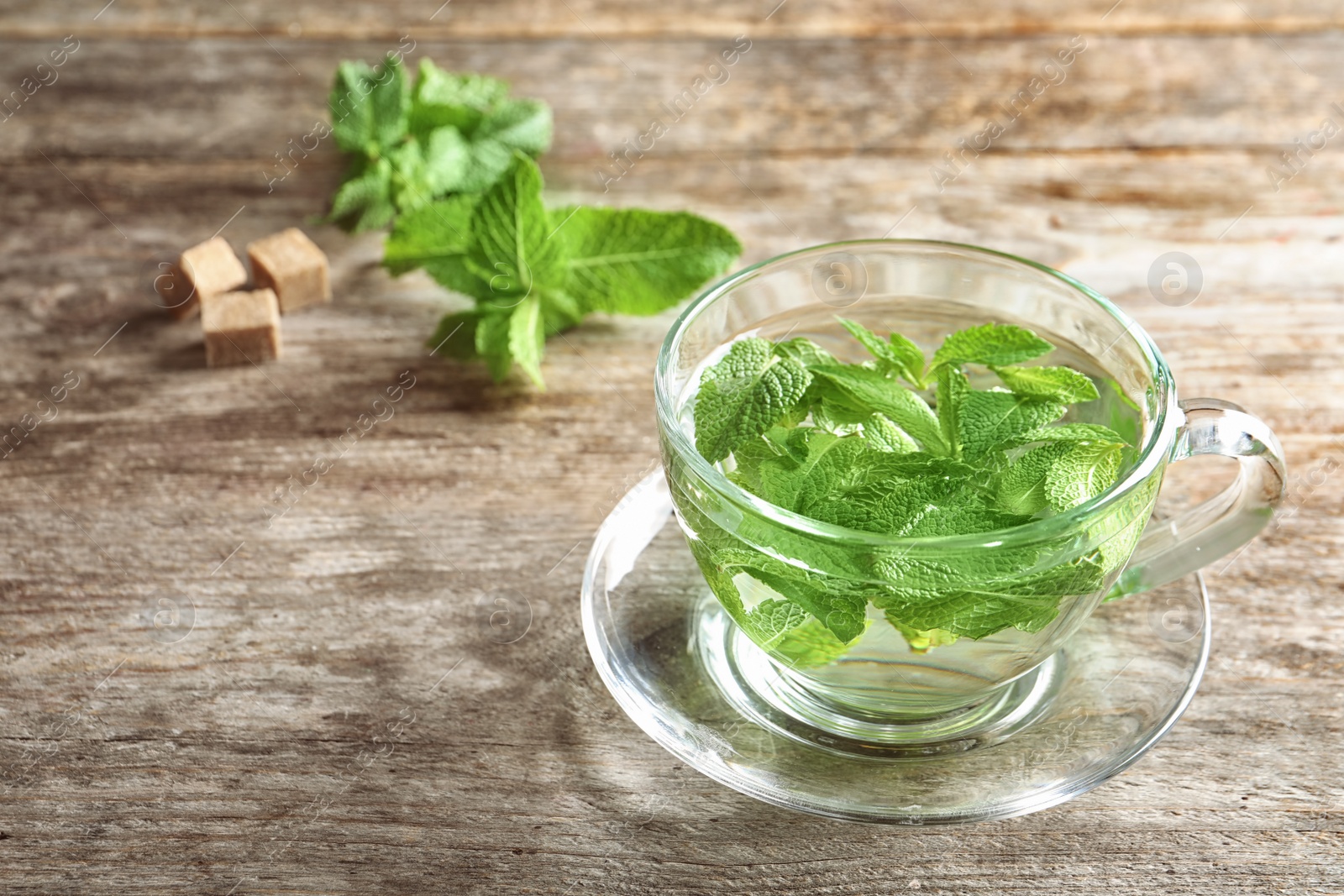 Photo of Cup with hot aromatic mint tea on wooden table