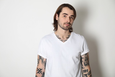 Photo of Young man with tattoos on arms against white background