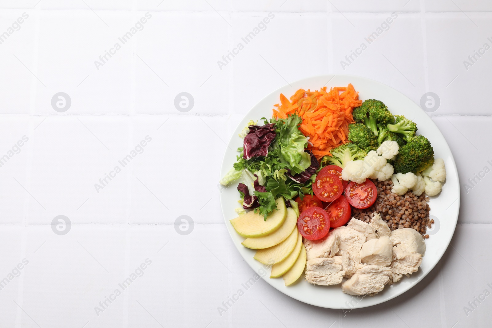 Photo of Balanced diet and healthy foods. Plate with different delicious products on white tiled table, top view. Space for text