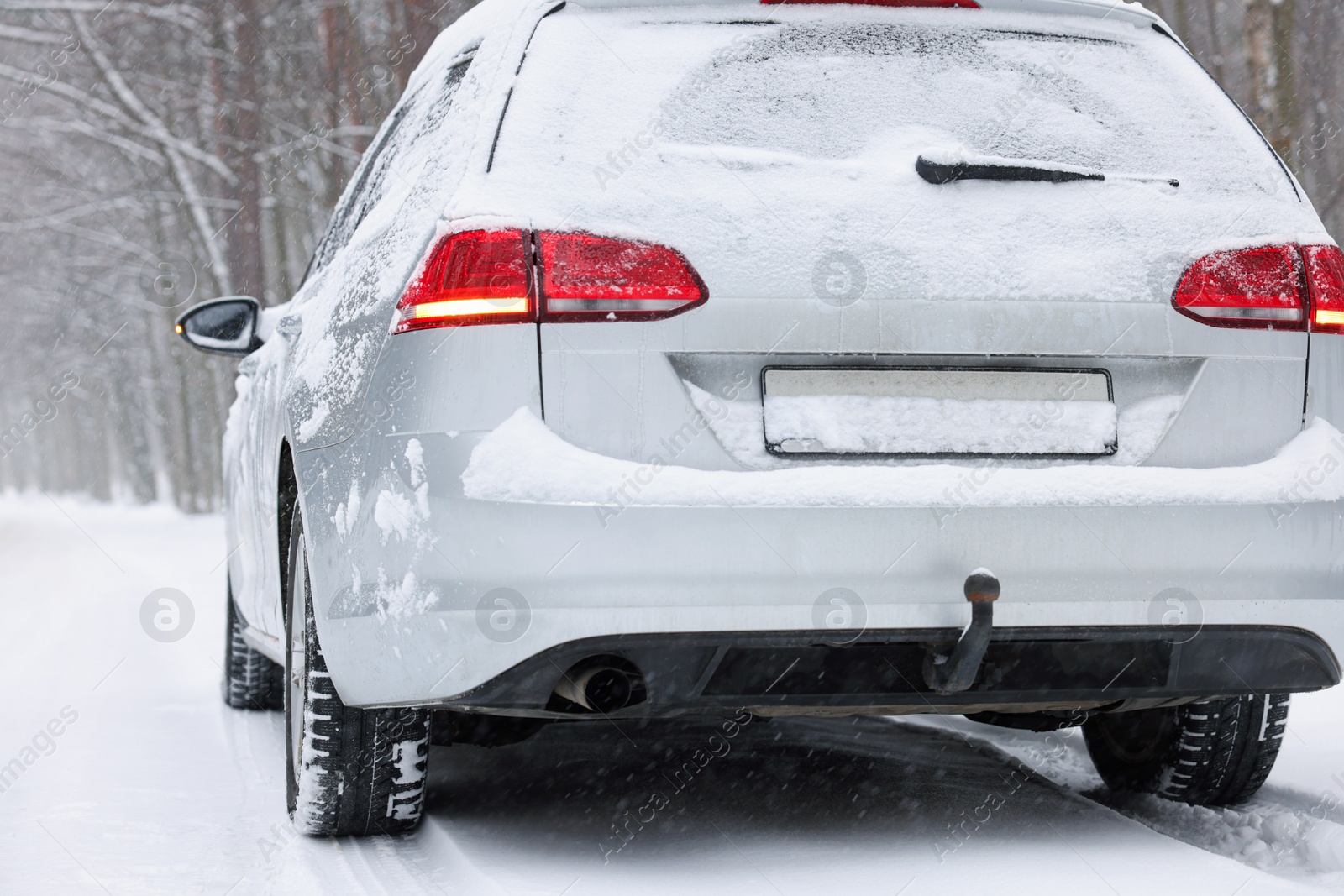 Photo of Car with winter tires on snowy road in forest