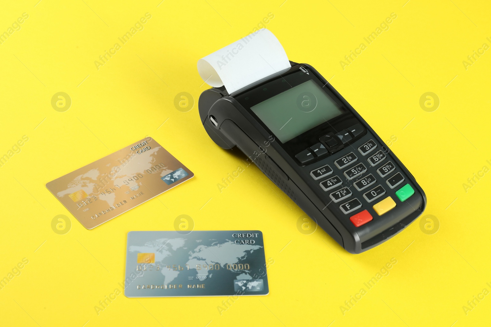 Photo of New modern payment terminal and credit cards on yellow background