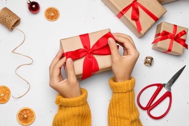 Photo of Young woman holding Christmas gift on white background, flat lay