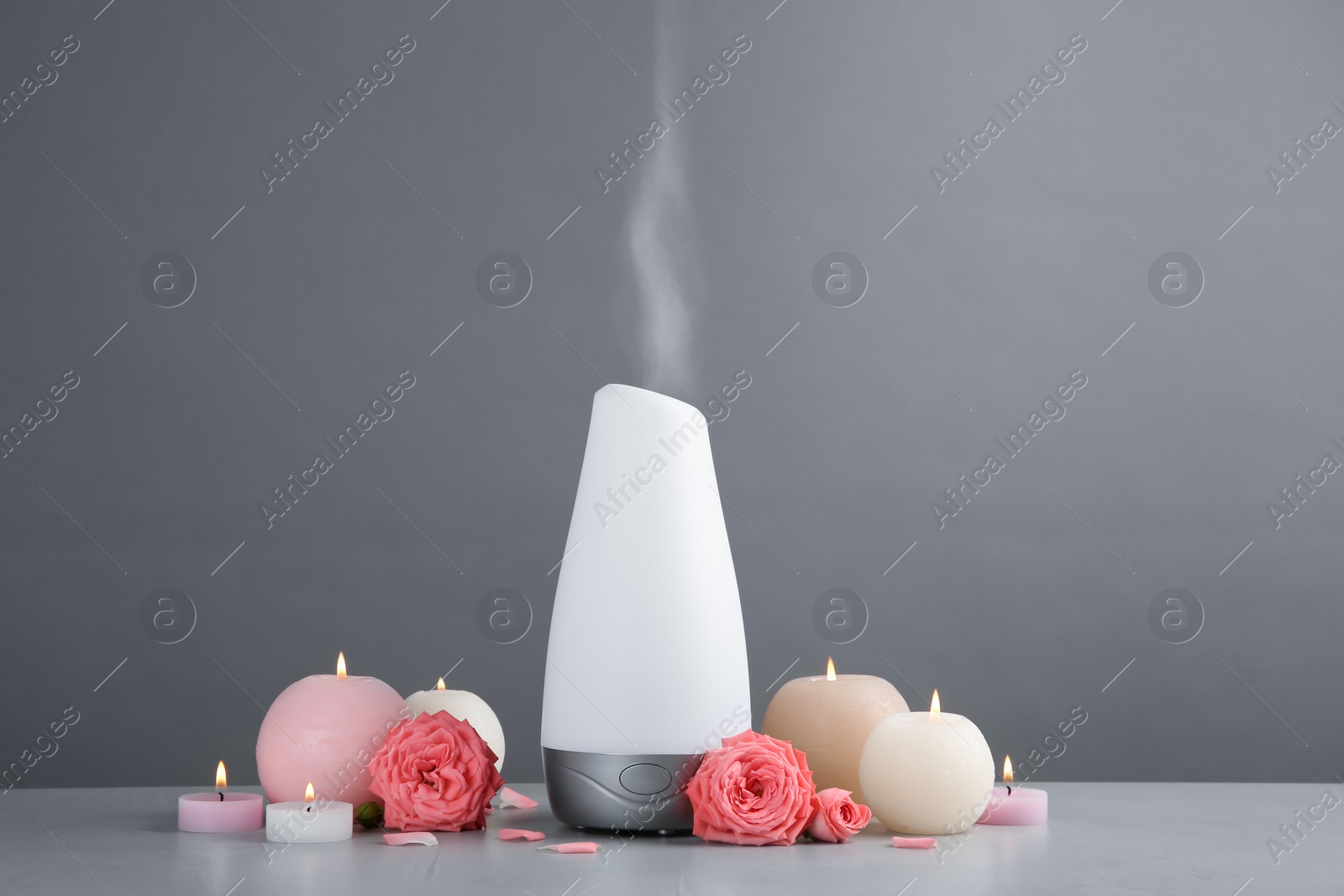 Photo of Composition with aroma humidifier on table against grey background. Space for text