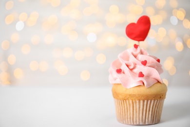 Tasty cupcake on white table against blurred lights, space for text. Valentine's Day celebration