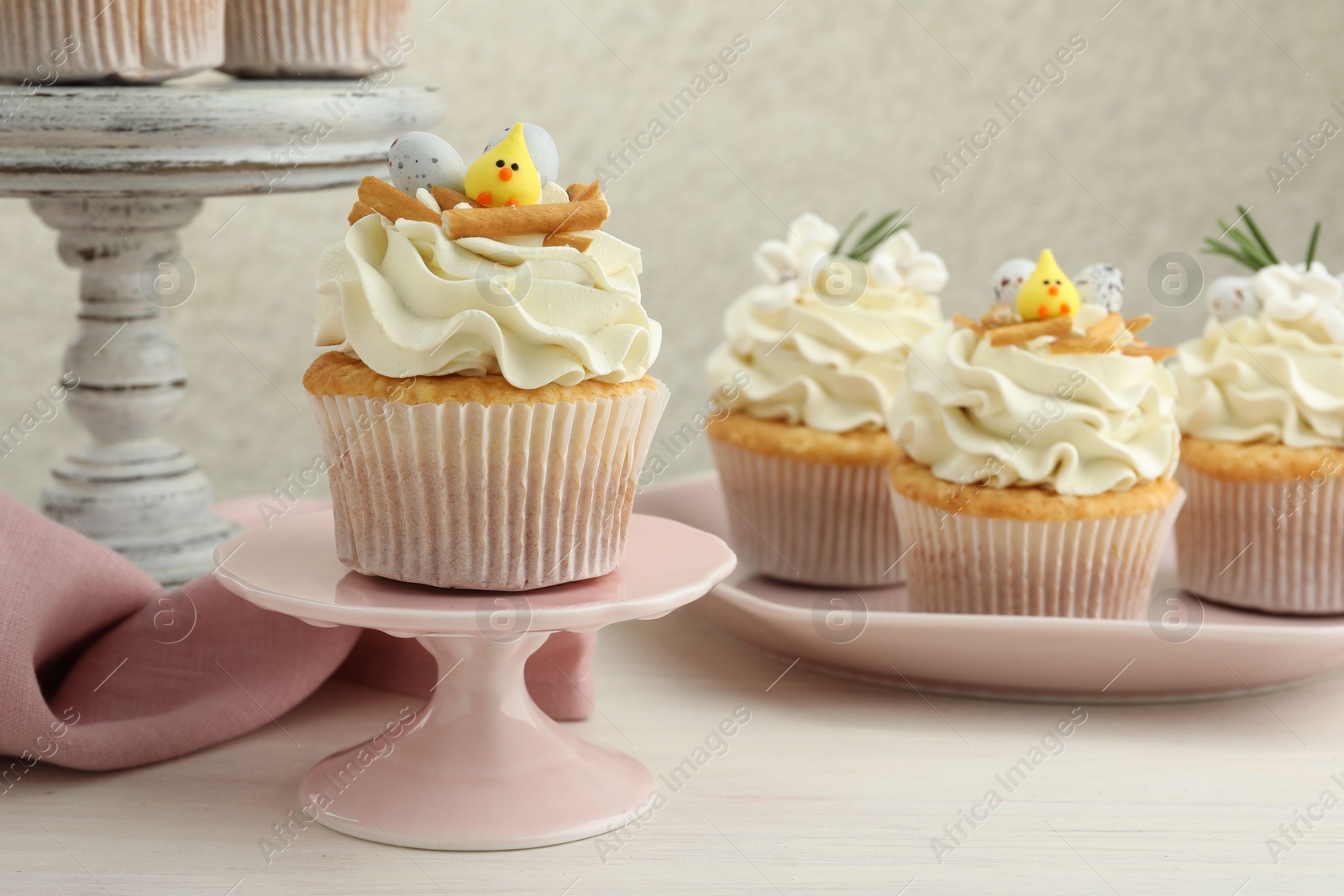 Photo of Tasty Easter cupcakes with vanilla cream on light wooden table