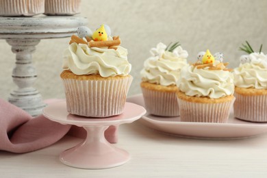 Photo of Tasty Easter cupcakes with vanilla cream on light wooden table