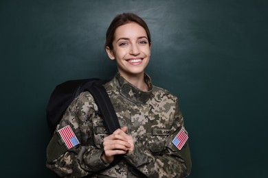 Female cadet with backpack near chalkboard. Military education