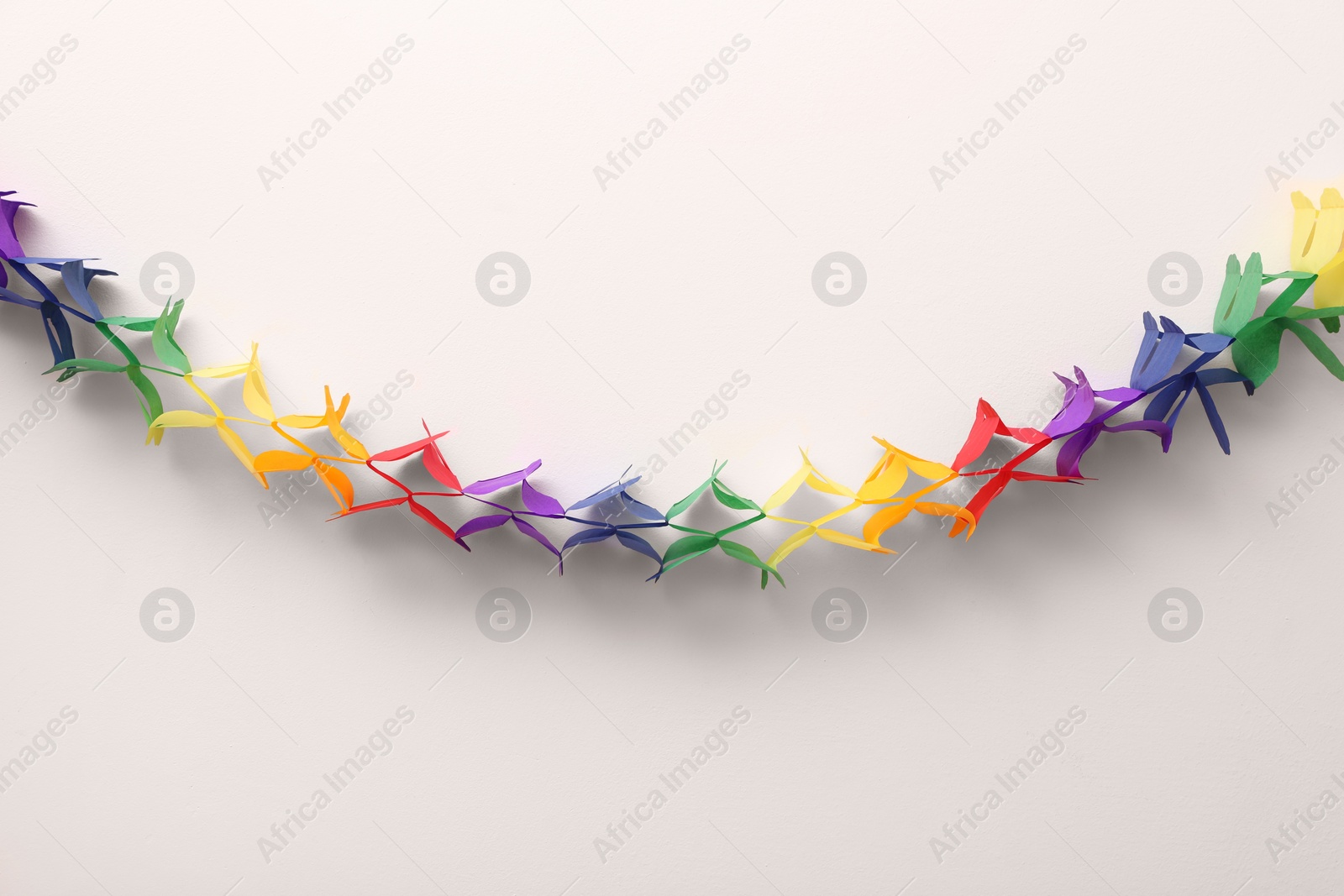 Photo of Rainbow paper garland on beige background. LGBT pride