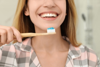 Photo of Woman brushing teeth in bathroom at home, closeup