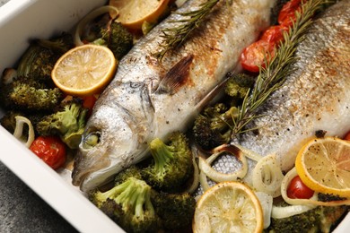 Photo of Delicious fish with vegetables and lemon in baking dish on table, closeup