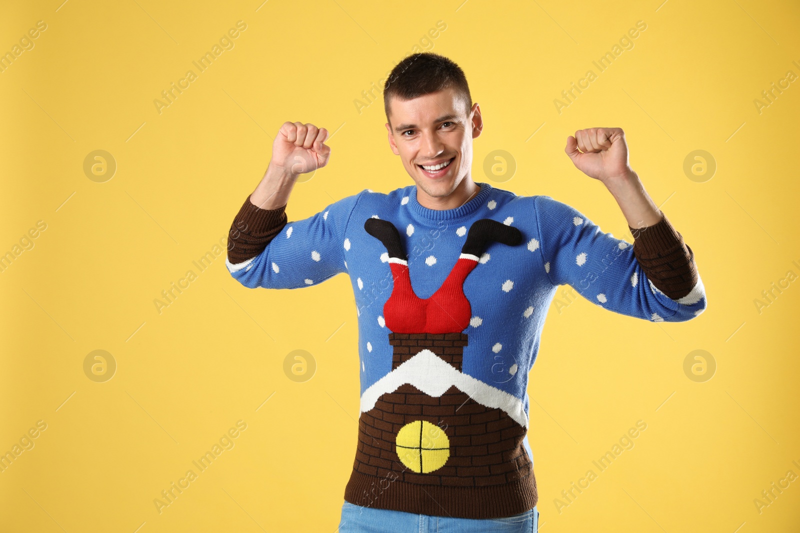 Photo of Portrait of happy young man in Christmas sweater on yellow background