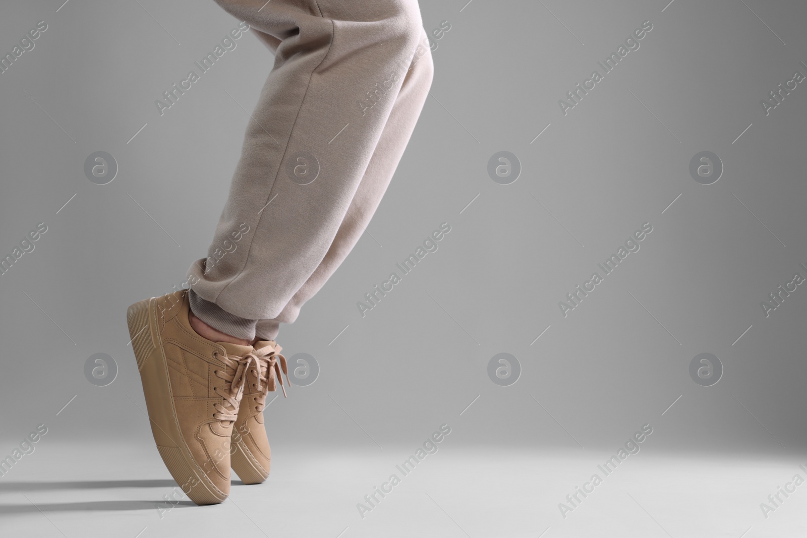Photo of Man wearing stylish sneakers on light grey background, closeup. Space for text