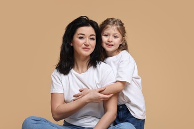 Photo of Beautiful mother with little daughter on beige background