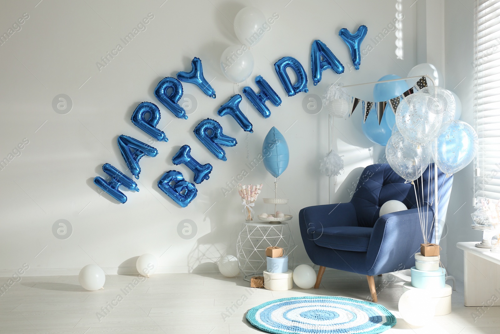 Photo of Phrase HAPPY BIRTHDAY made of blue balloon letters in decorated room