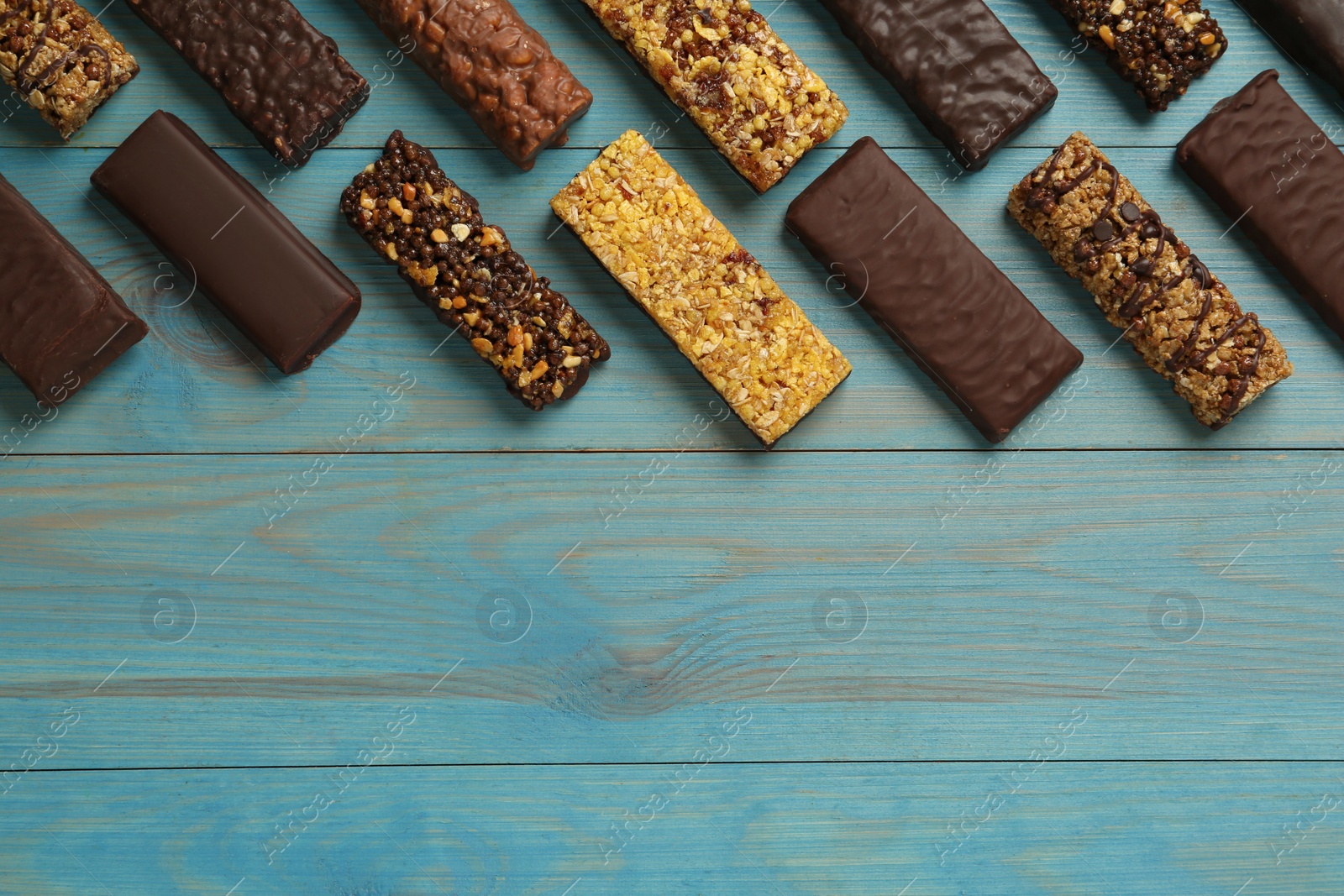 Photo of Different tasty protein bars on light blue wooden table, flat lay. Space for text