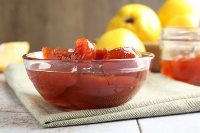 Photo of Tasty homemade quince jam in bowl on tiled table, closeup