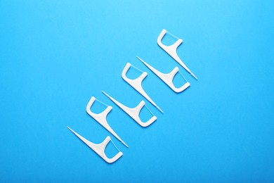Photo of Dental flossers on light blue background, flat lay. Mouth hygiene