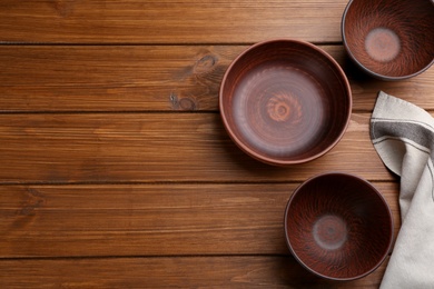 Photo of Clay bowls on wooden table, flat lay with space for text. Handmade utensils