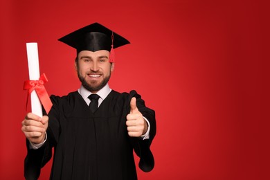 Happy student with graduation hat and diploma on red background. Space for text