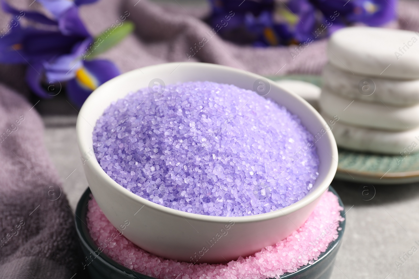 Photo of Different types of sea salt and spa stones on grey table, closeup