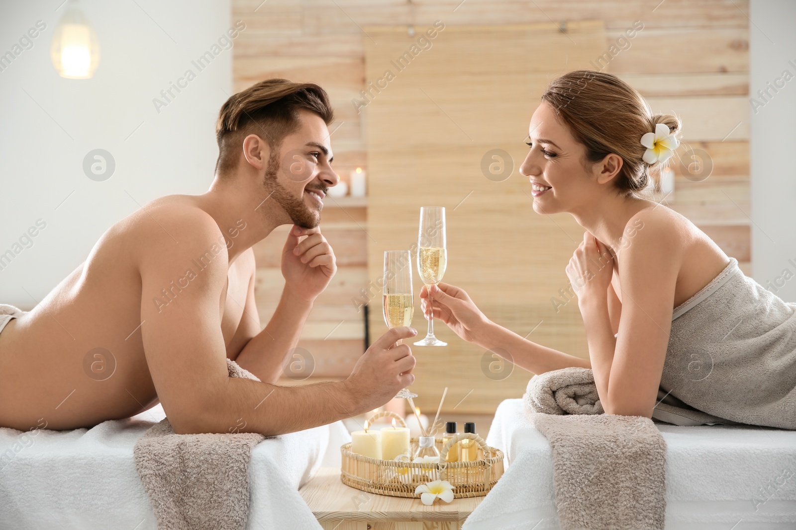 Photo of Romantic young couple with champagne in spa salon