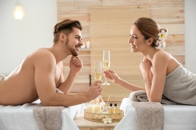 Romantic young couple with champagne in spa salon