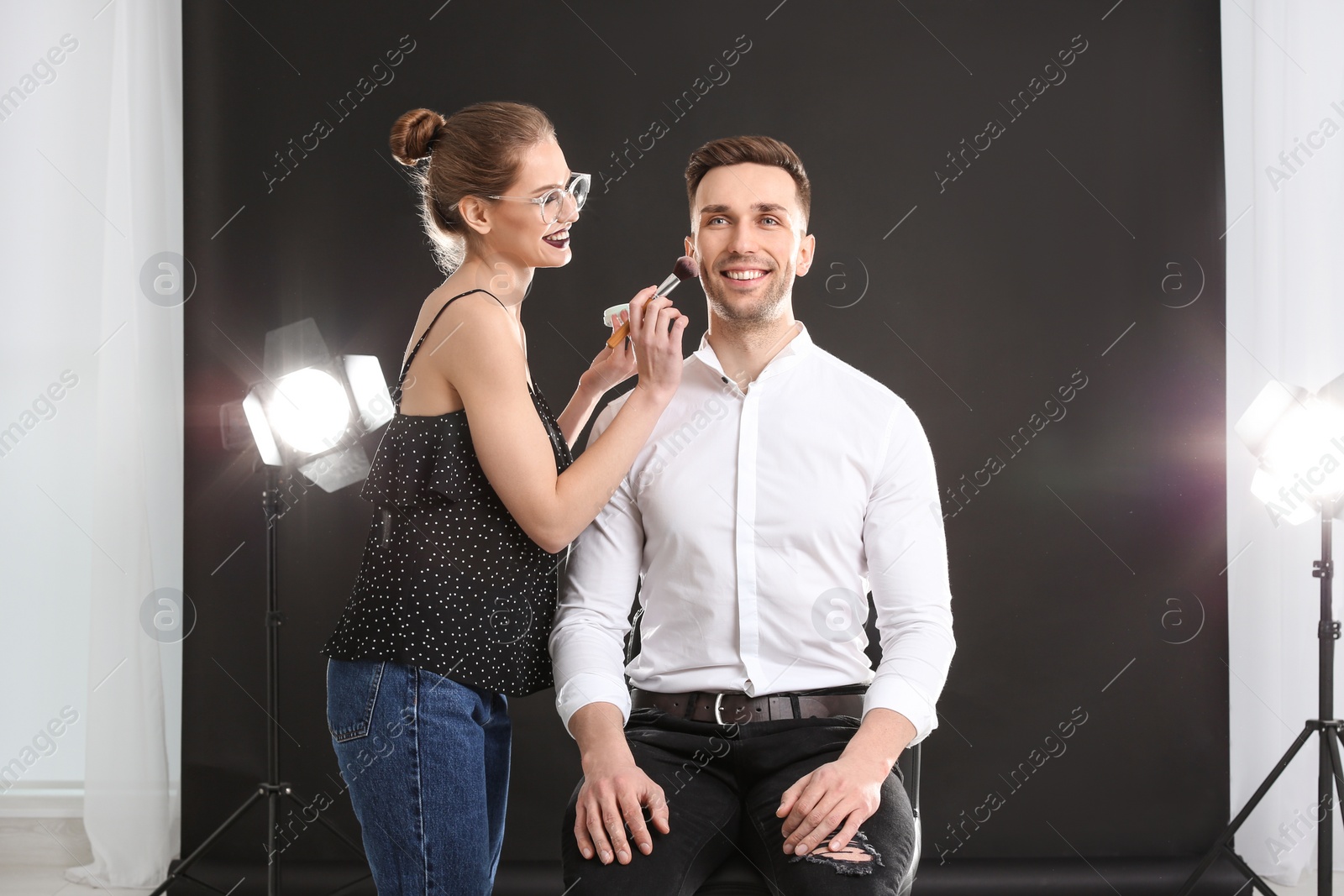 Photo of Professional makeup artist working with  young man in photo studio