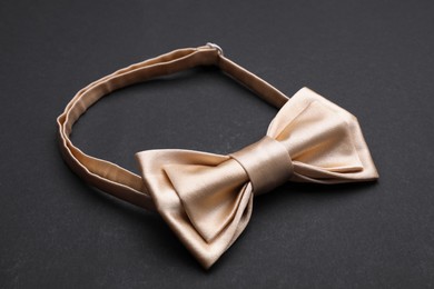 Stylish beige bow tie on black background