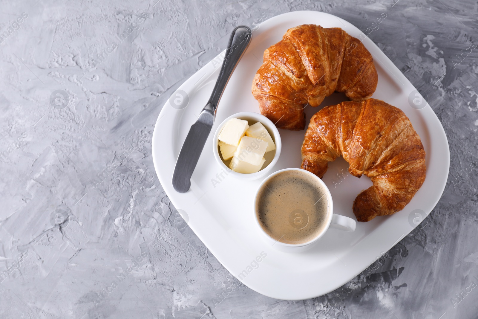 Photo of Tasty breakfast. Cup of coffee, butter and fresh croissants, top view. Space for text