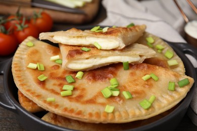 Delicious fried chebureki with cheese and green onion on wooden table, closeup