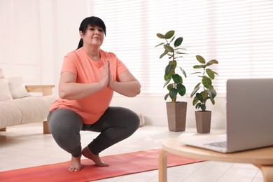 Photo of Overweight mature woman practicing yoga at home, space for text