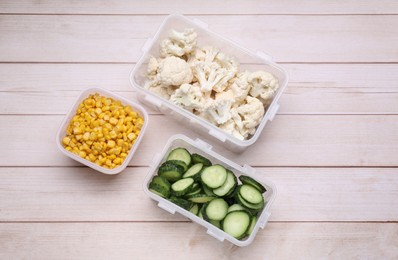 Plastic containers with different fresh products on white wooden table, flat lay