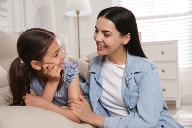 Photo of Young mother and her daughter on sofa in living room. Adoption concept