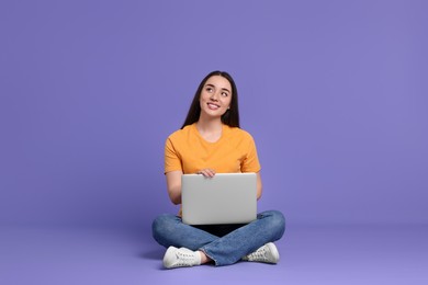 Photo of Smiling young woman with laptop on lilac background