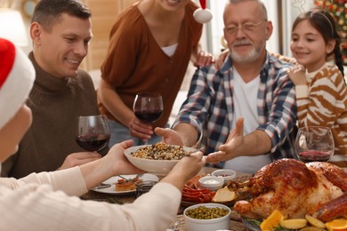 Photo of Woman giving bowl of traditional Christmas Slavic dish kutia to man during festive dinner at home