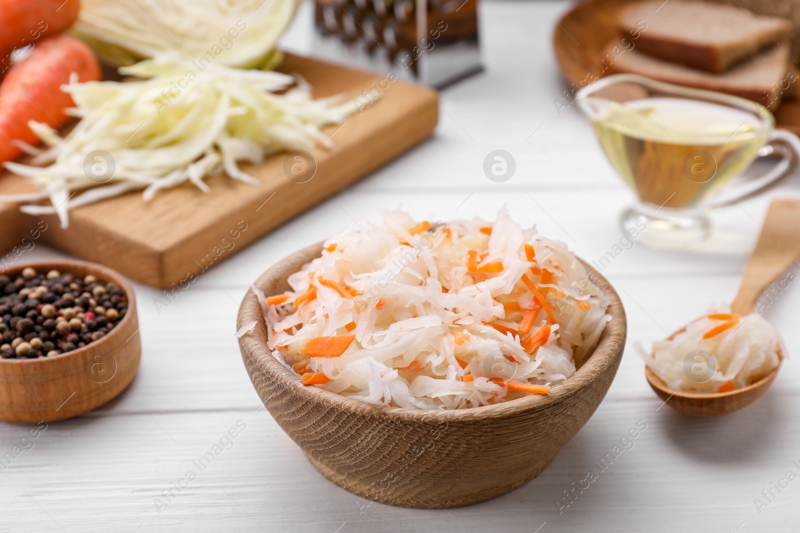 Photo of Bowl of tasty sauerkraut on white wooden table