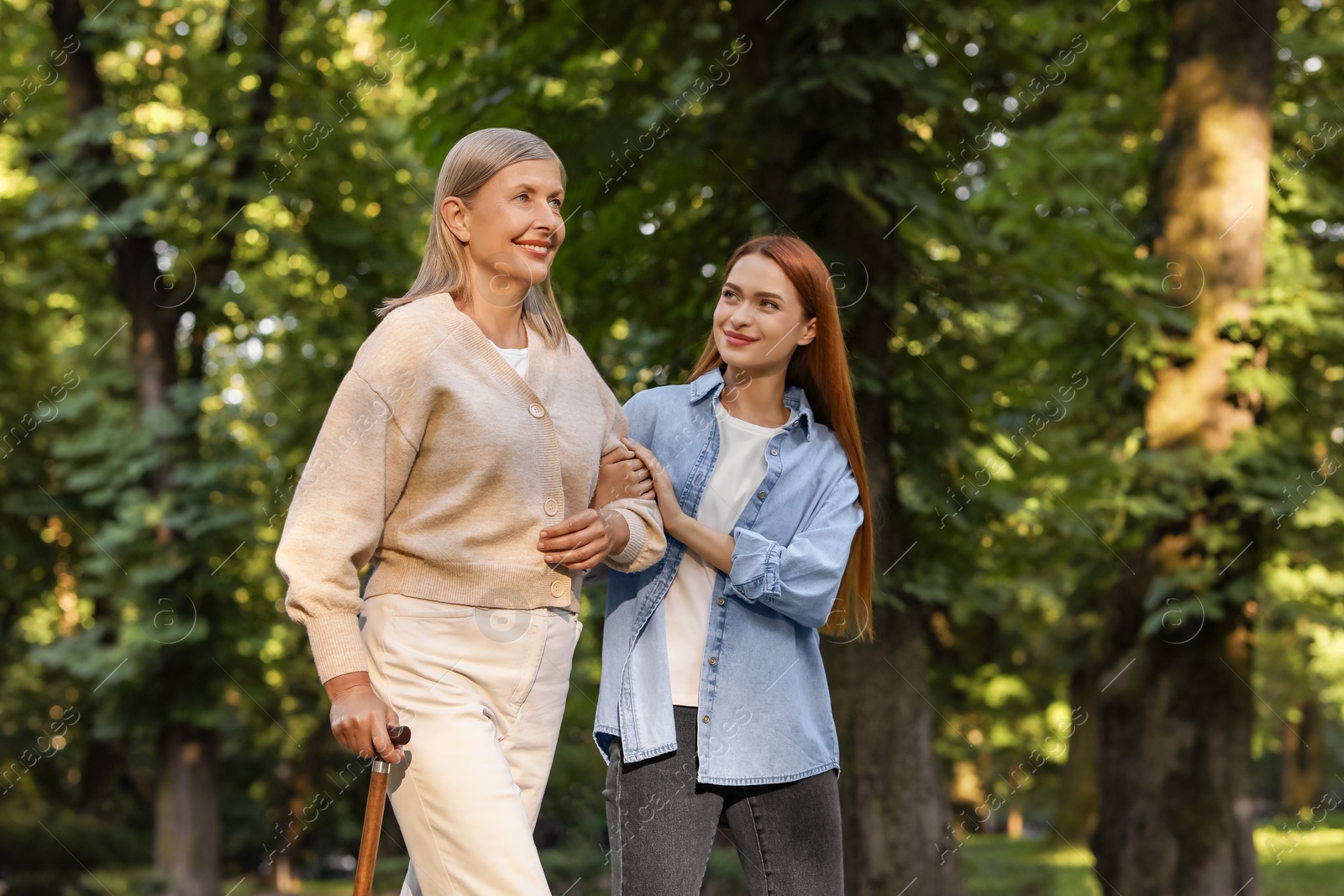 Photo of Senior lady with walking cane and young woman in park. Space for text