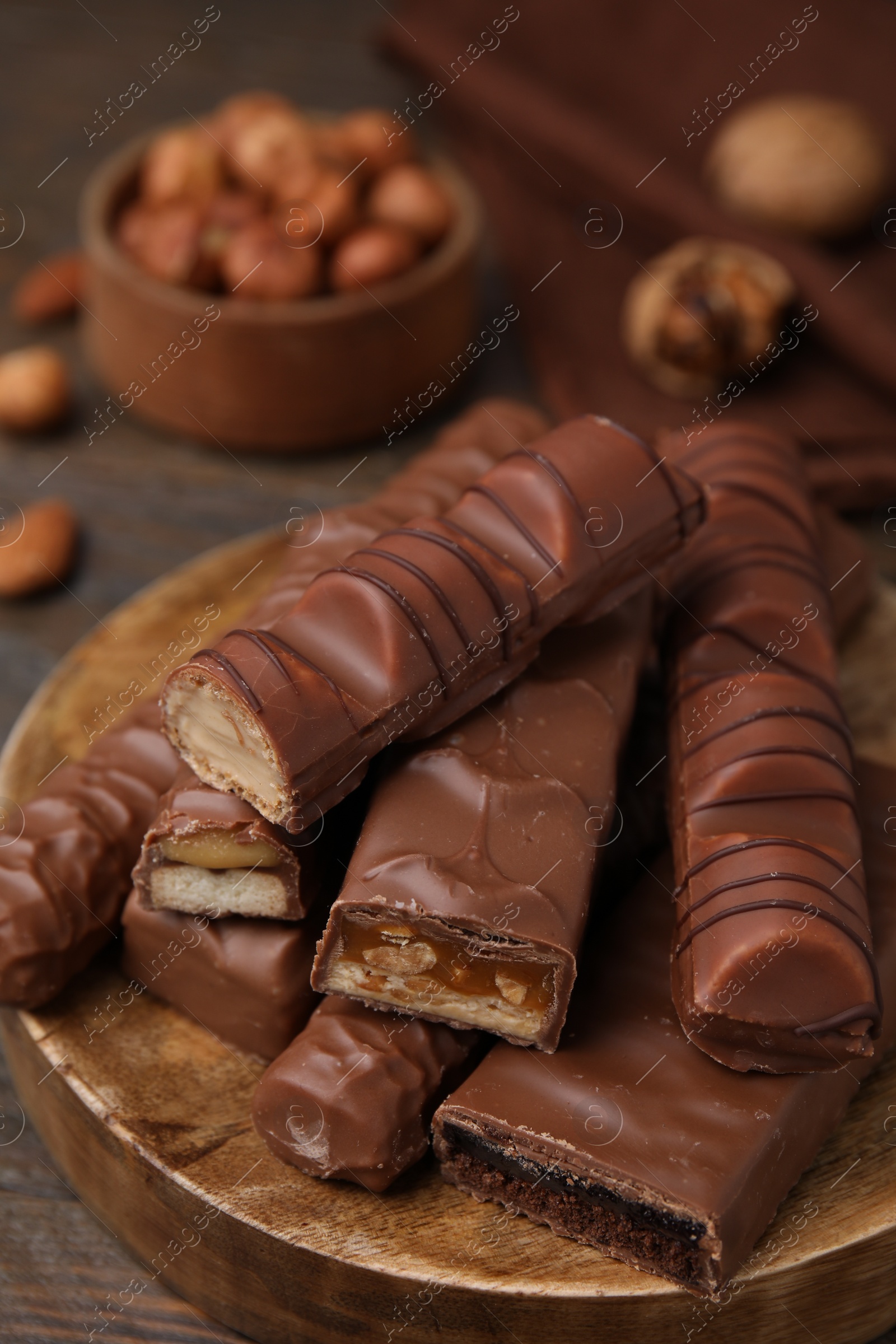 Photo of Pieces of different tasty chocolate bars on wooden board, closeup