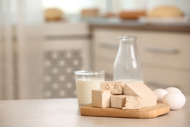 Photo of Pieces of compressed yeast and dough ingredients on white table indoors, space for text