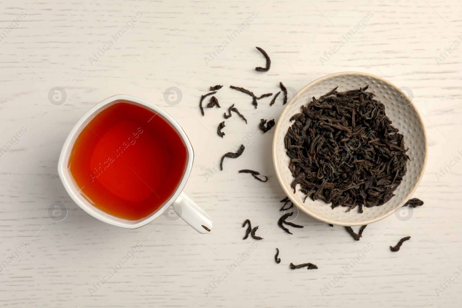 Photo of Cup of delicious tea with dried leaves on wooden background, top view