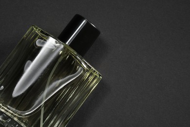 Photo of Luxury men`s perfume in bottle on black background, top view. Space for text